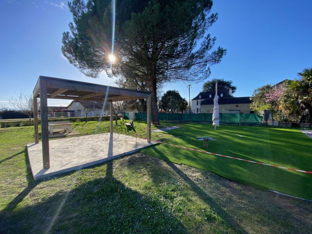 Pergola autoportante sur terrasse dallée dans un grand jardin