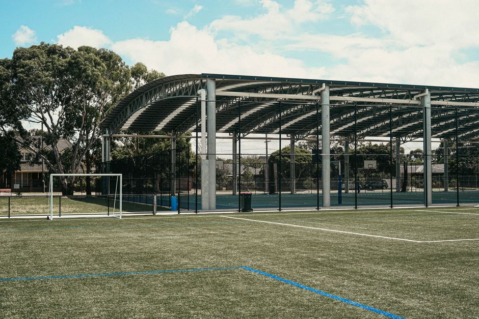 Terrain multisport clôturé avec buts de football et paniers de basket
