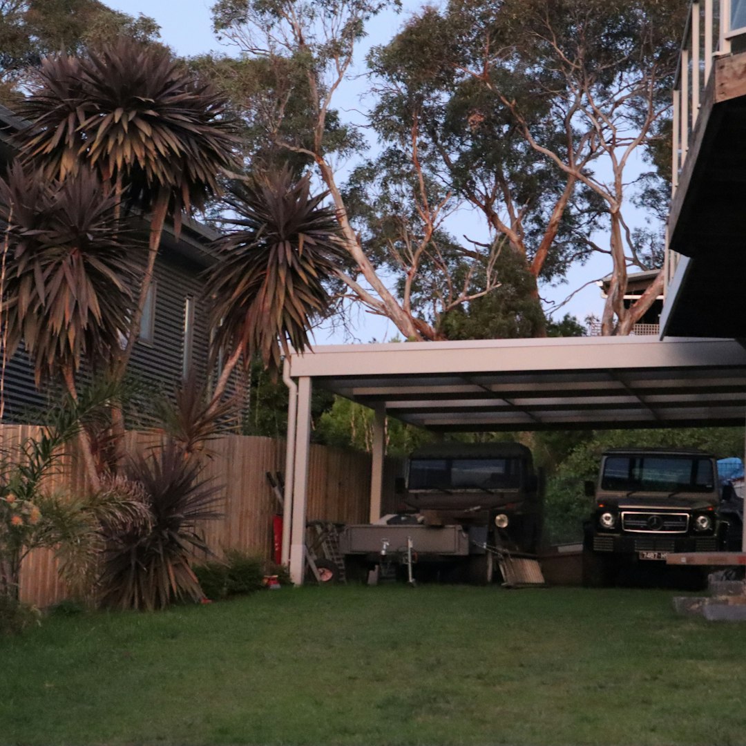 Carport à toit plat abritant deux véhicules dans un jardin