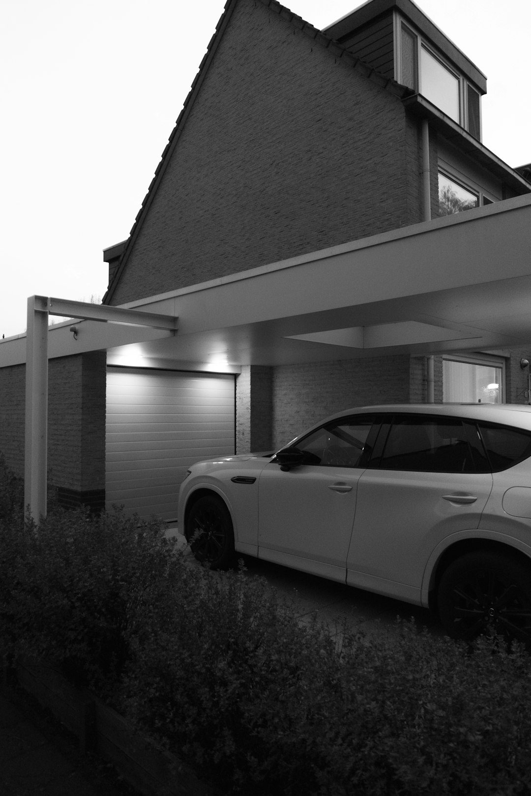Carport contemporain adossé à une maison, voiture stationnée à l'abri